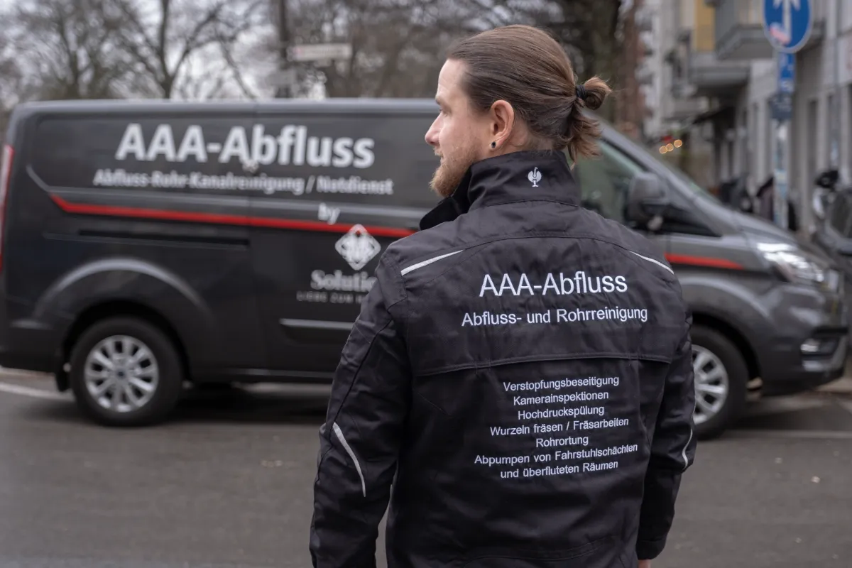 Arbeitsjacke von AAA-Abfluss mit Leistungsübersicht vor dem Einsatzfahrzeug in Berlin